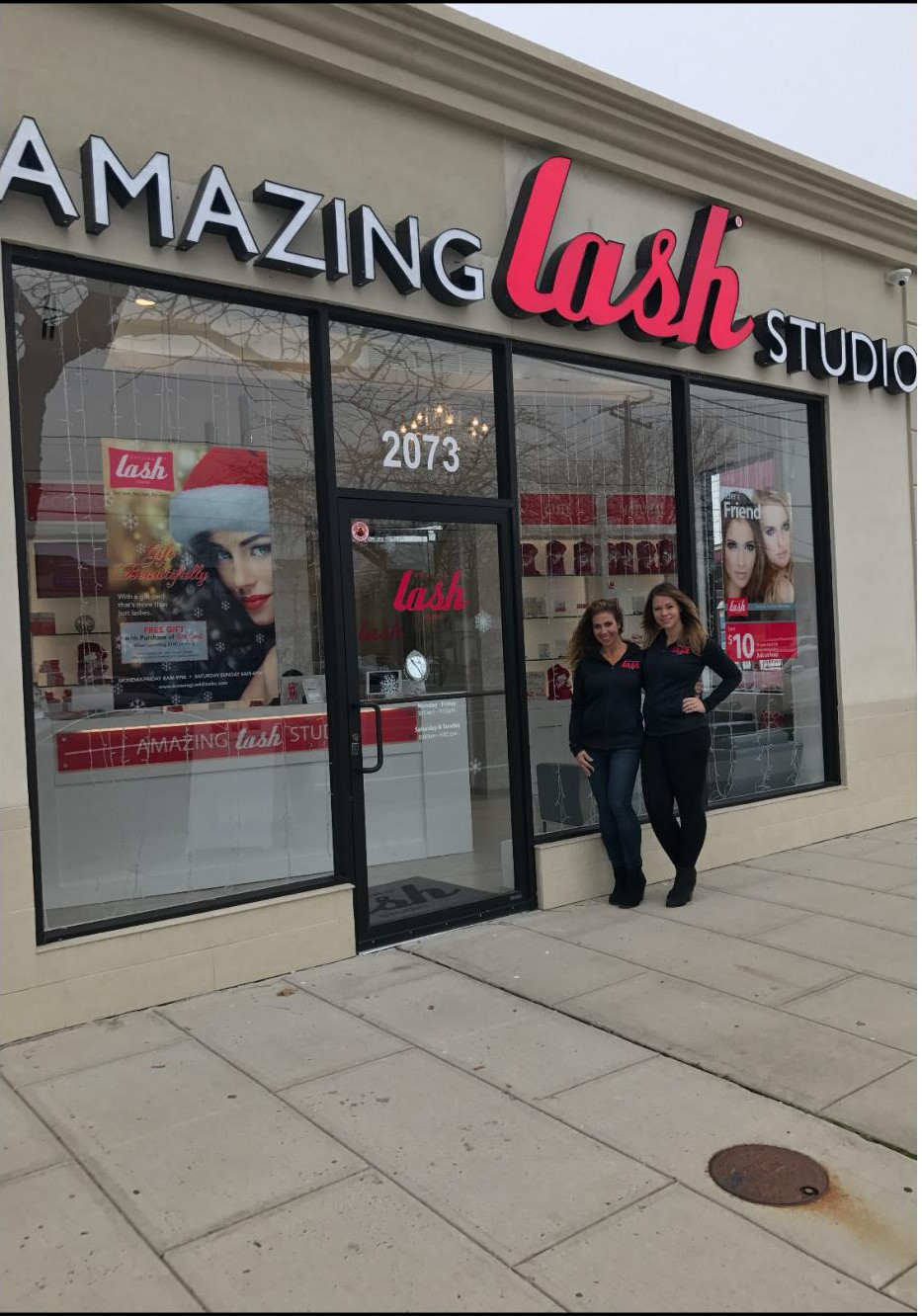 Amazing Lash Studio storefront with owner and manager posing by door