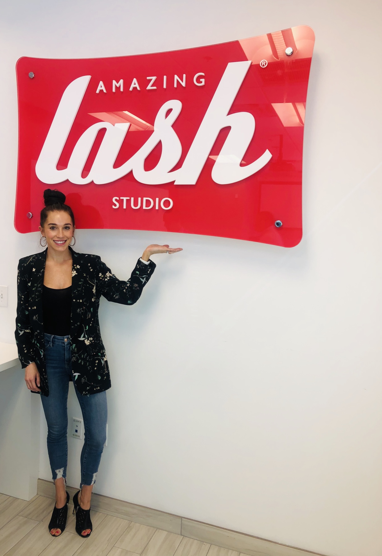 Amazing Lash Owner posing in front of lobby signage