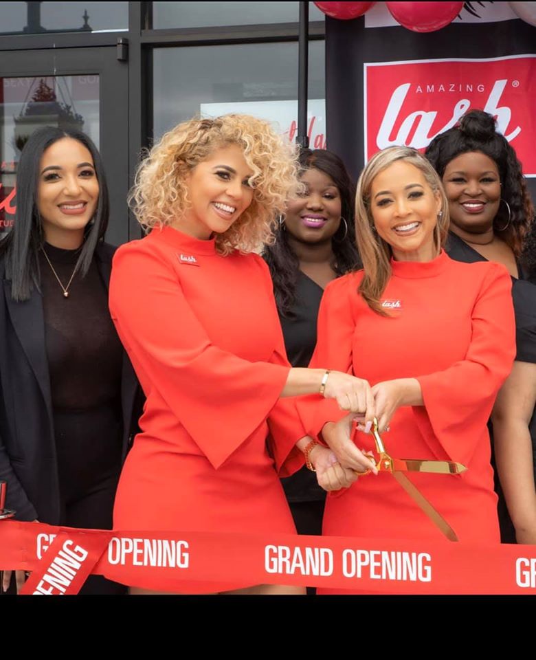 two women posing with scissors to cut ribbon